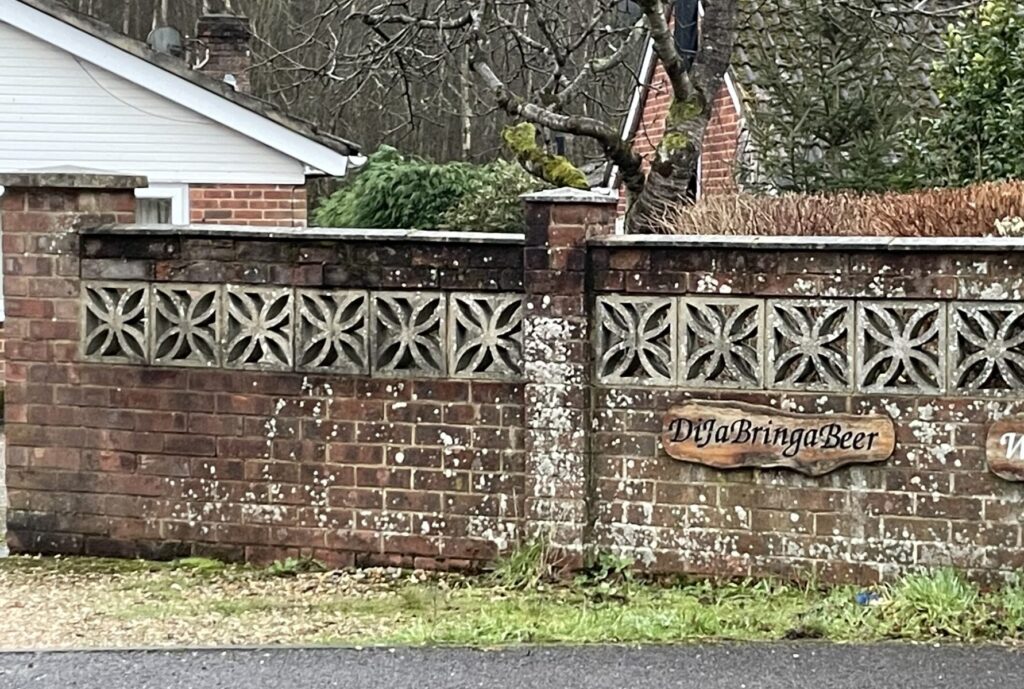 Garden wall with a wooden name plate for a house that reads "DiJaBringaBeer"